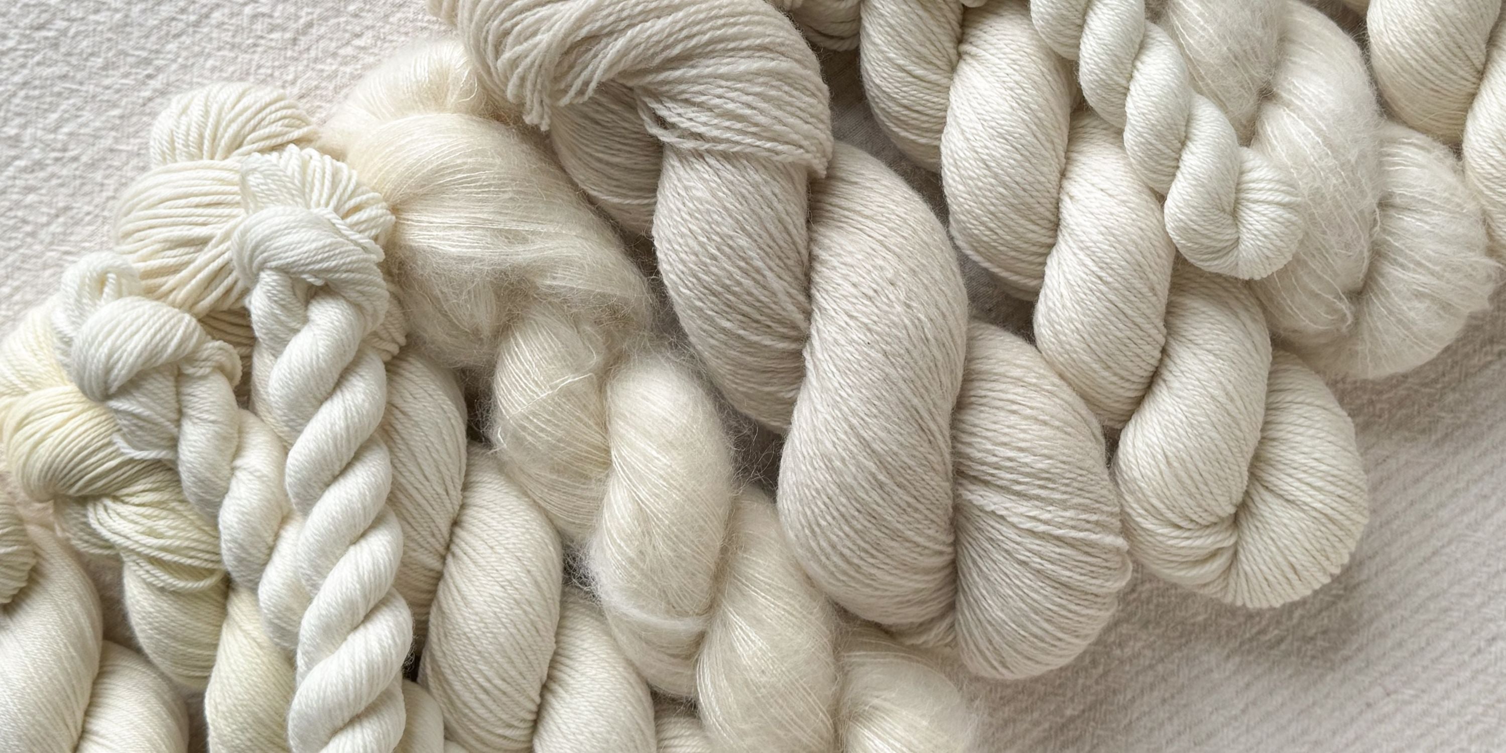Close-up of cream-colored yarn skeins on a textured surface